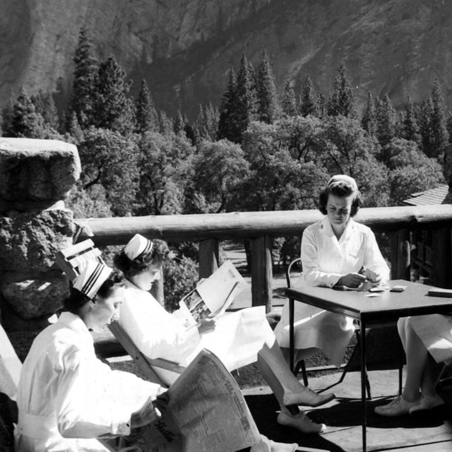 a nurse and sailors on patio; mountain in background