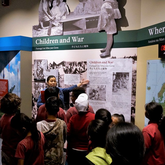 Ranger talking to a school group in front of an exhibit about children and war