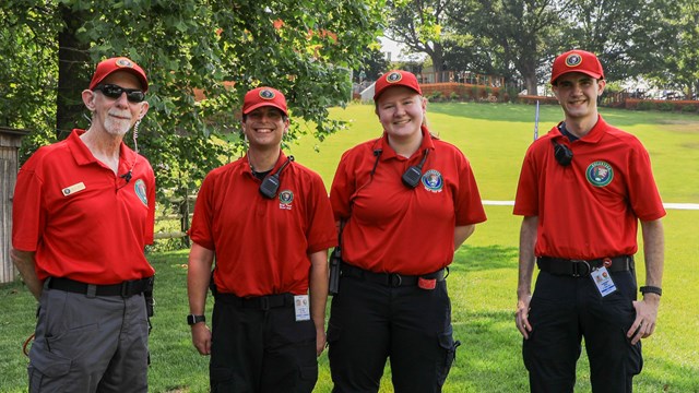 Four EMS volunteers pose outside in a green lawn area.