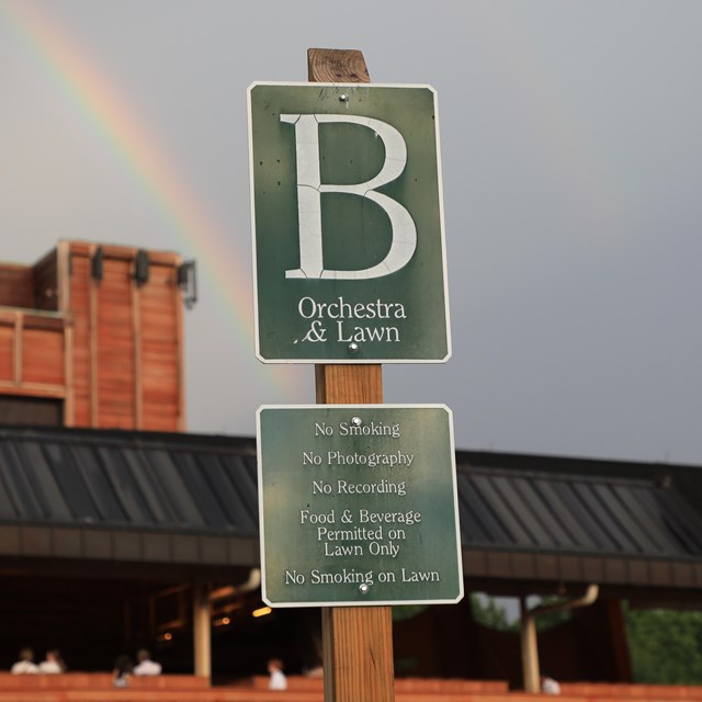 Green sign with House rules with Filene Center in the background