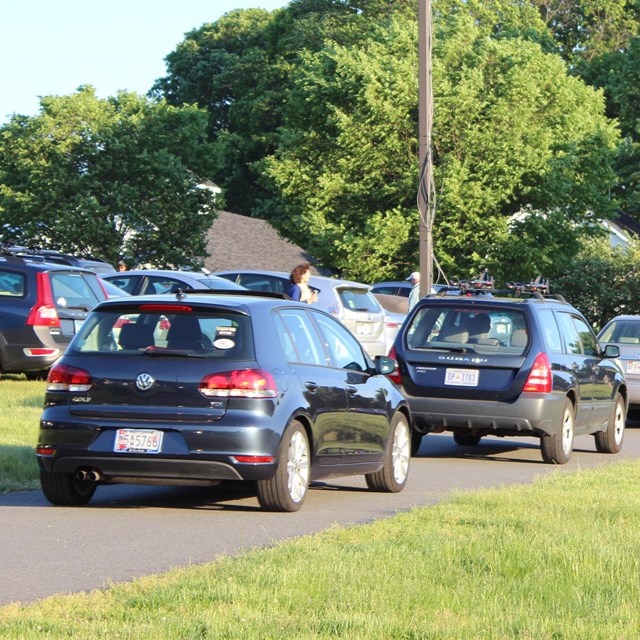 Cars in a line to be parked on grass hill