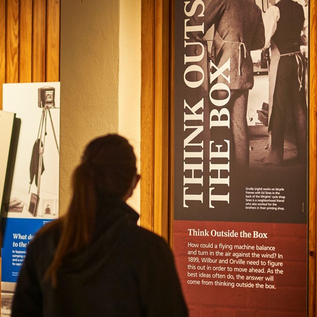 A woman standing and reading an exhibit labeled 
