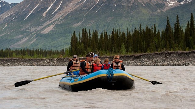 A group of people in an inflatable boat on a river.