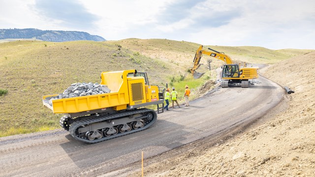 large construction vehicles on a newly paved roadway
