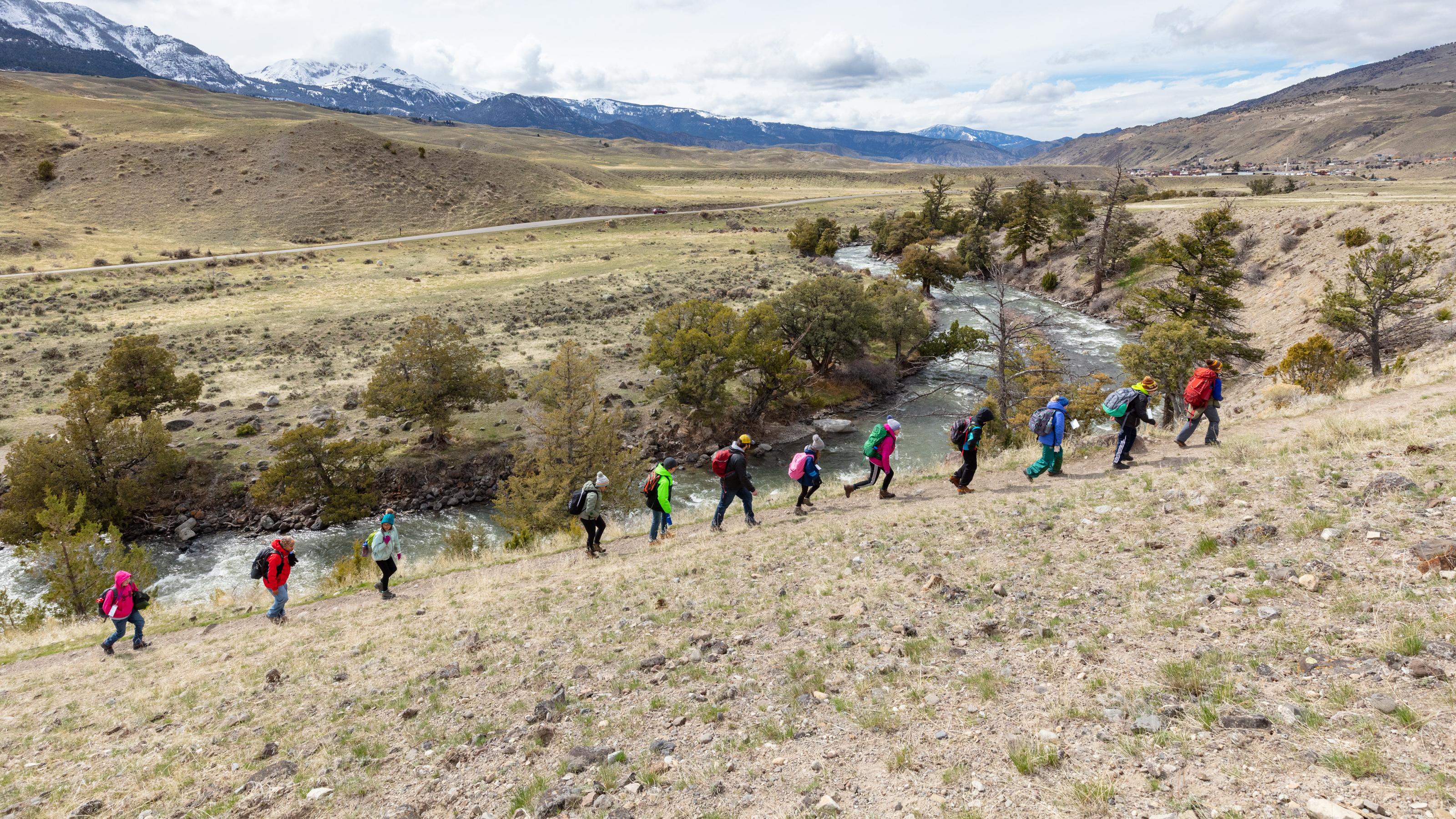 Students hike along a trail near a river.