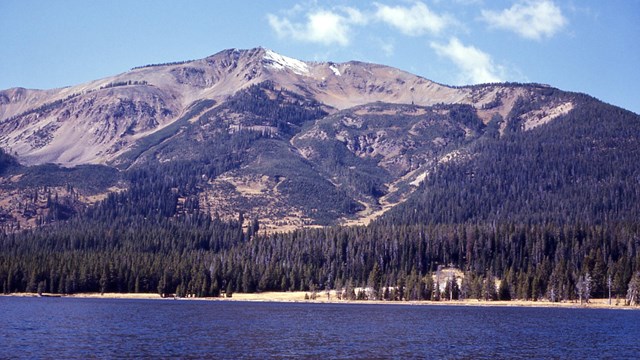 Tall mountain rises near the shore of an alpine lake.