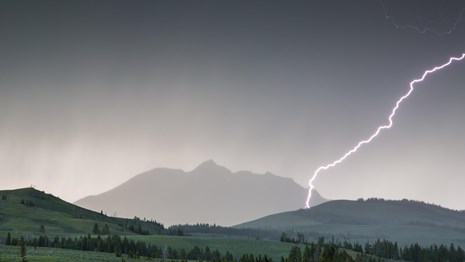 Lightning strikes Electric Peak as a dark storm rolls over the mountain.