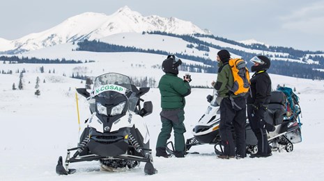 Snowmobilers stop to take photos of Electric Peak at a Swan Lake Flats pull-out.