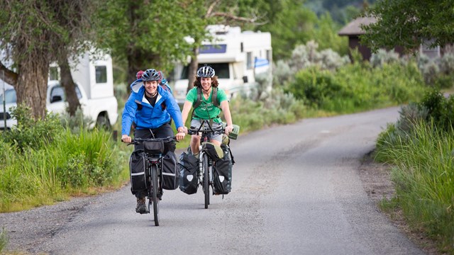 Cyclists pedal around a campground