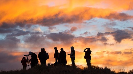 A group of people gather during sunrise