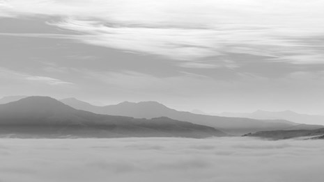 Black and white photograph of low-lying clouds and distant mountain peaks.