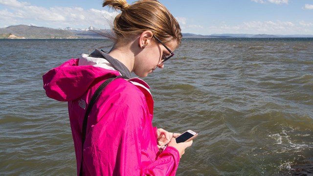Someone using a cell phone by Yellowstone Lake.