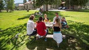A family sits around a picnic table and enjoys a meal together.