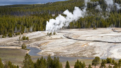 View from the top of a building shows a steaming geyser.