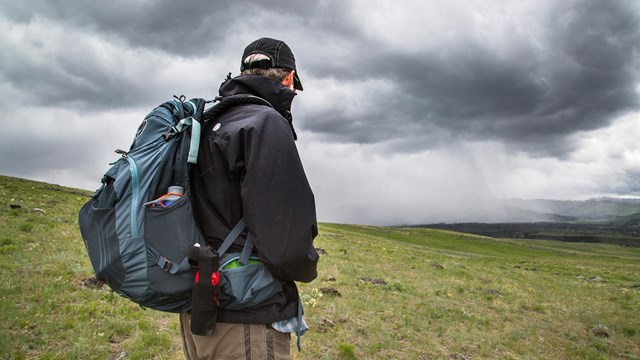 A hiker watches an approaching storm on Specimen Ridge