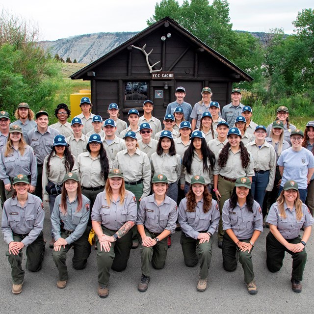 A large group of people in matching uniforms smiling on a summer day