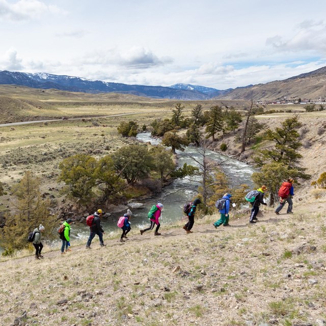 Students hike along a trail near a river.