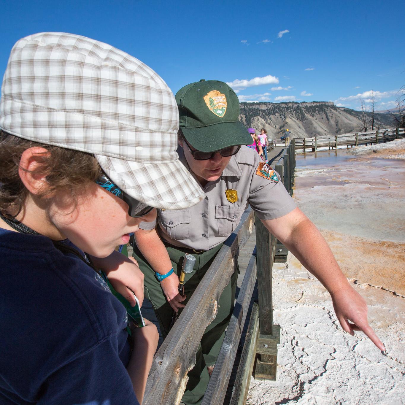 A ranger points out a hot spring to a young person