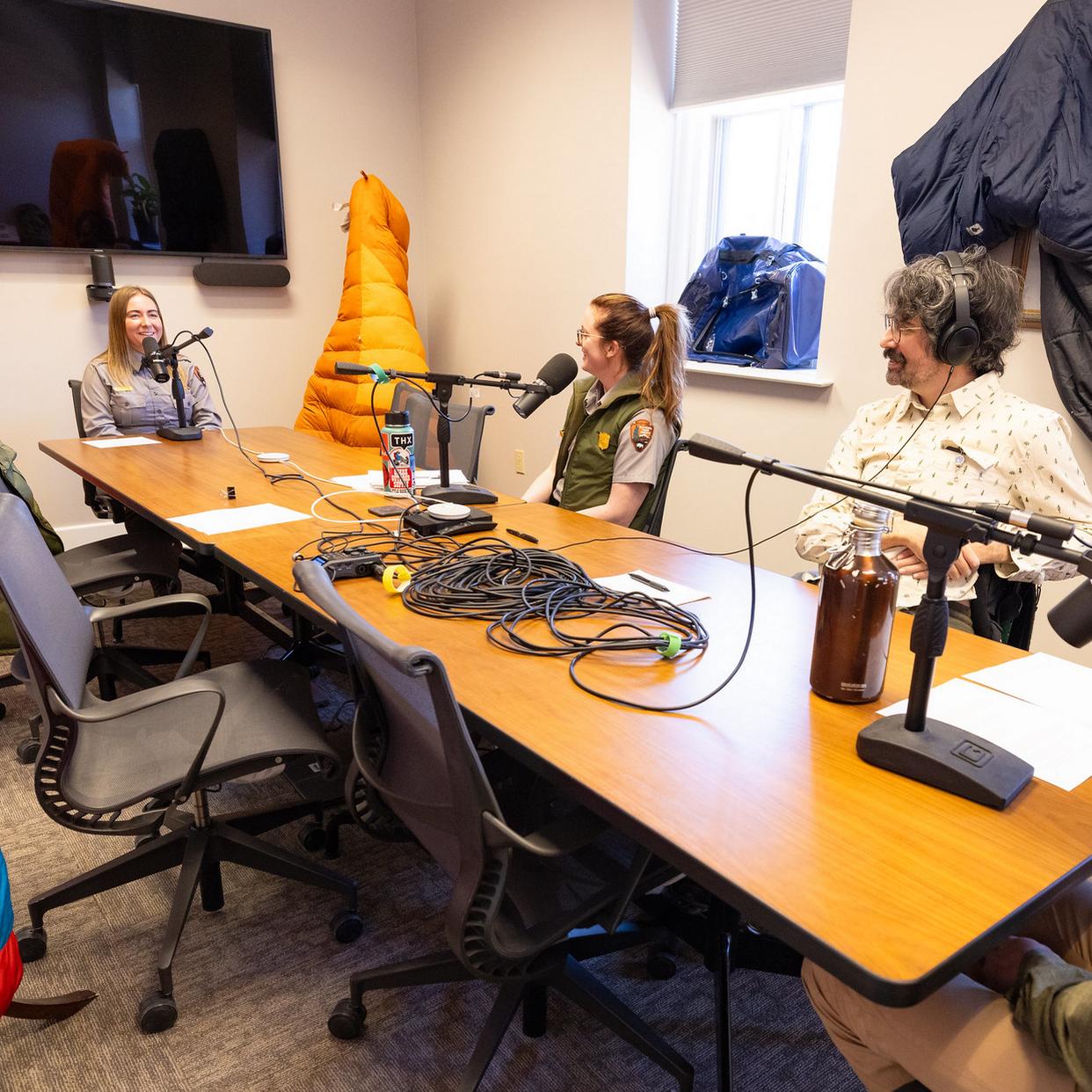 four park rangers talking into microphones around a conference table
