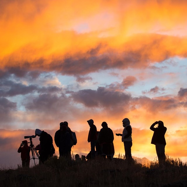 A group of people gather during sunrise