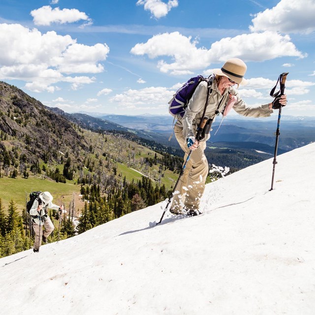 A hiker walks up a snowy mountain side.