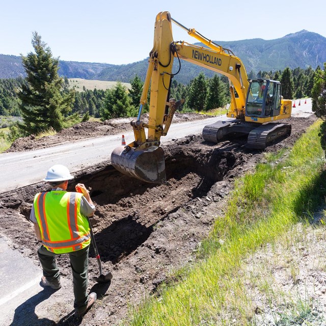 A large piece of machinery digging a hole to repair a road