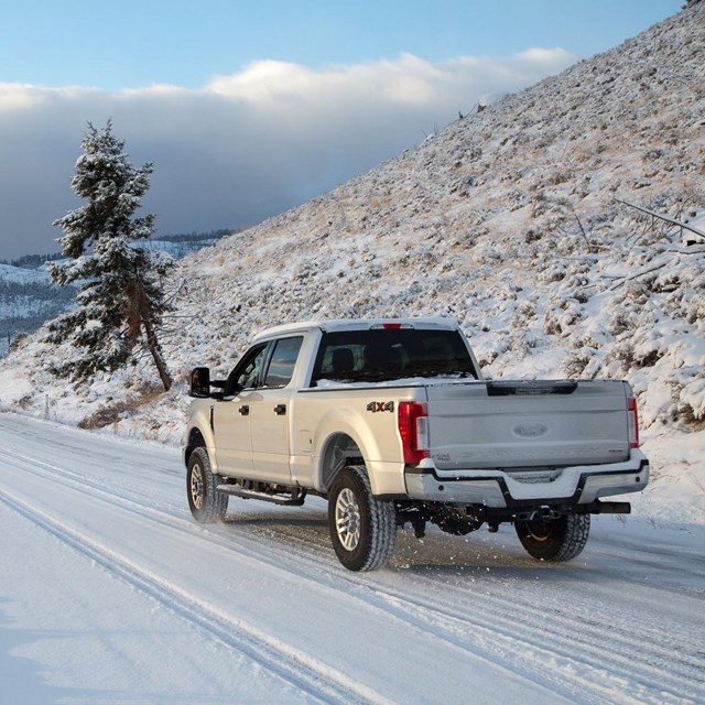 A truck drives down a snow-covered road.