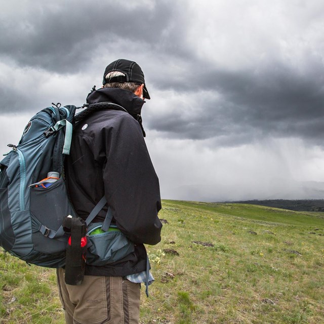A hiker watches an approaching storm on Specimen Ridge