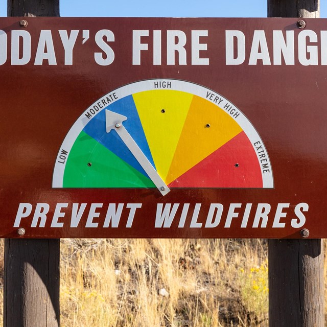 A large, brown, metal road sign that reads: 