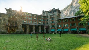 The back lawn of the Ahwahnee Hotel, a large wood and stone building.