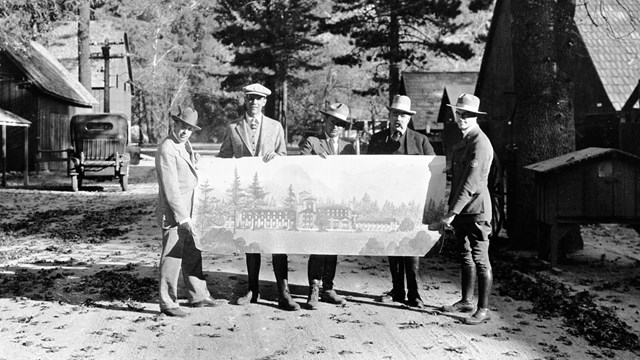 4 men holding a sketch of a building