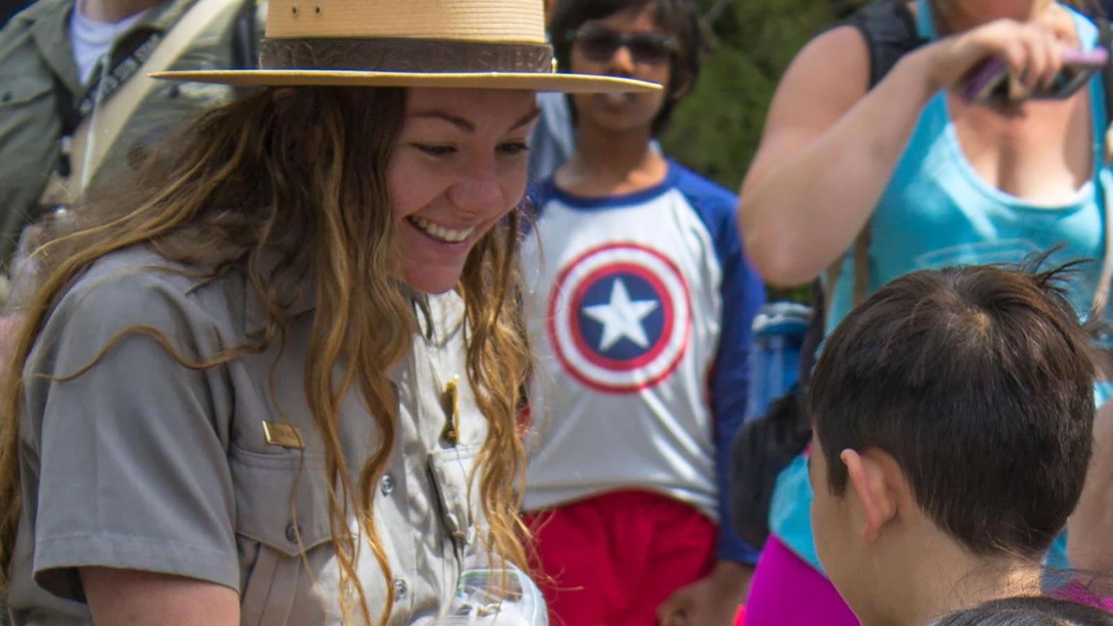 Ranger handing out a Junior Ranger badge to a child on Junior Ranger Day