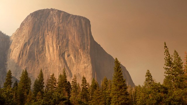 El Capitan rises through smoke from a wildfire
