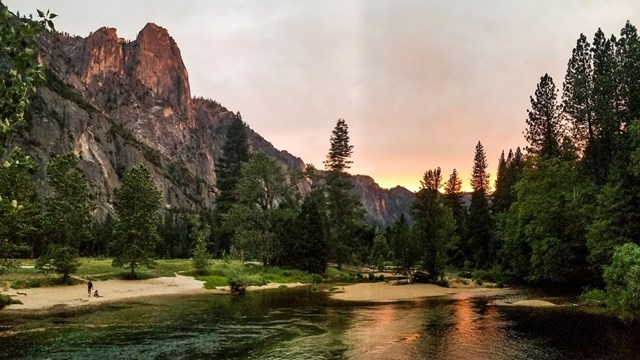 Merced River in Yosemite Valley at sunset with Sentinel Rock and sandy beach