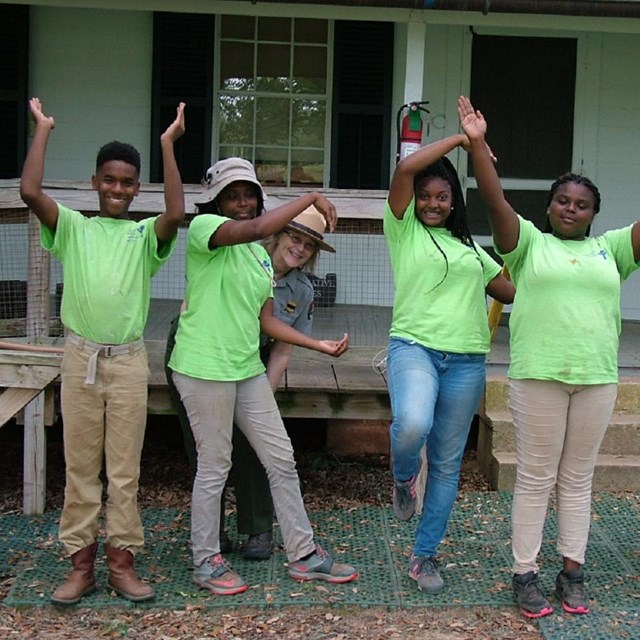 A group of Youth Conservation Corps with a ranger outside of a historic building