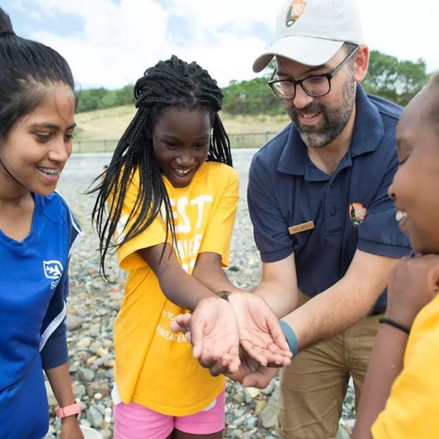 youth campers with adults wearing yellow and blue shirts outdoors