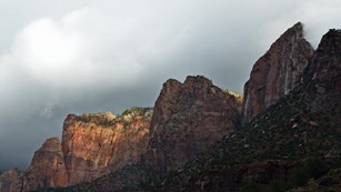 Red sandstone cliffs with grey storm clouds.