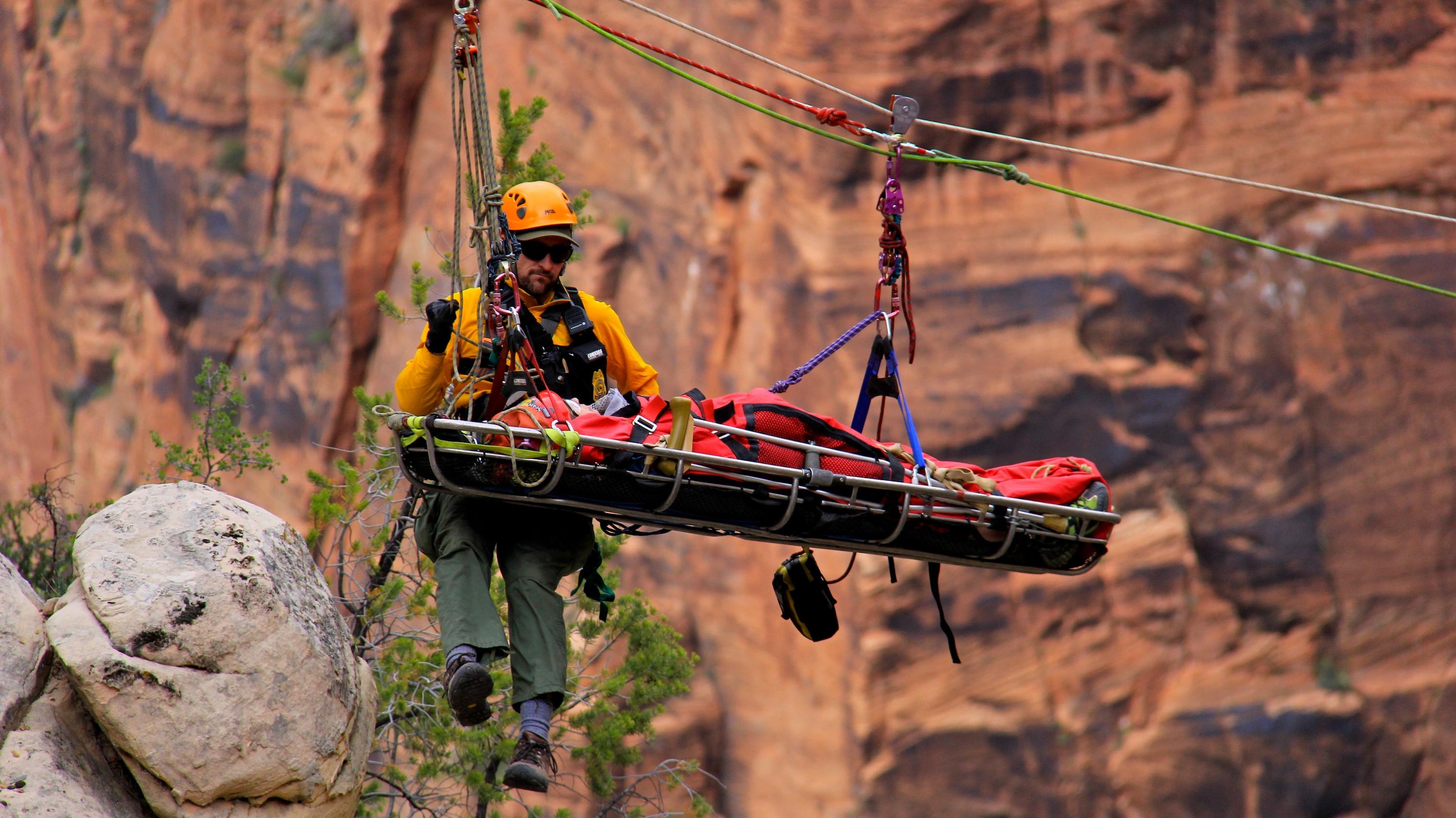 A search and rescue crew lowers a person down the canyon via highline.