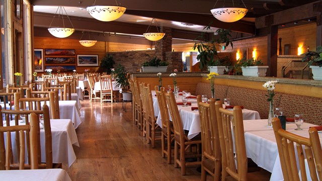 Wooden tables and chairs with round lights overhead in a restaurant.