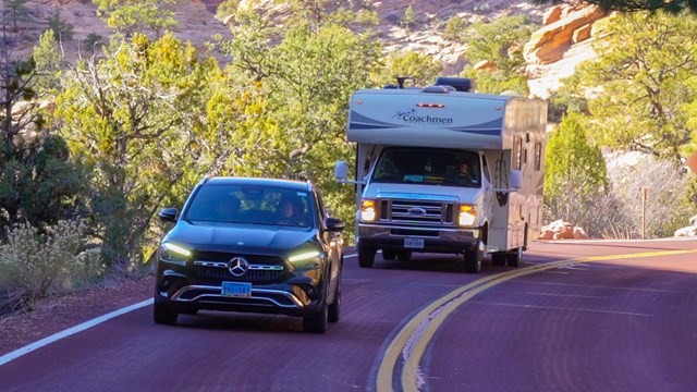 A recreational vehicle drives between two cars on the Zion-Mt. Carmel Highway.
