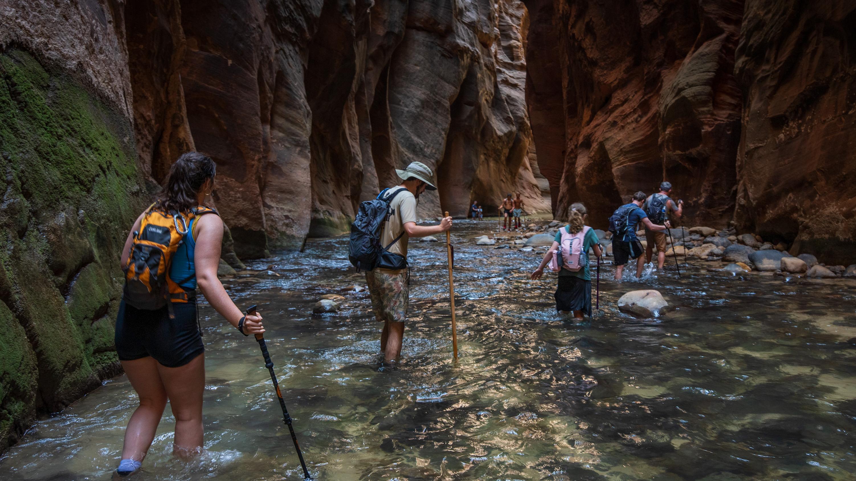 A group of hikers walk through ankle-deep, rushing water.