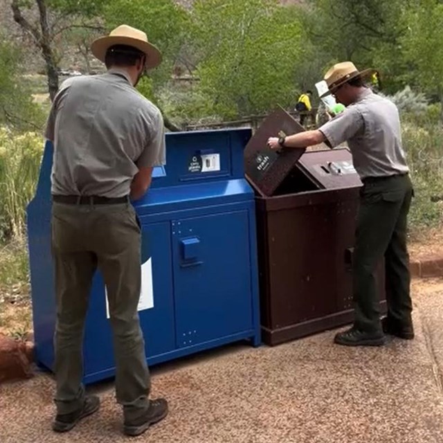 Two rangers throw trash and recycling into the properly marked bins at the Visitor Center.