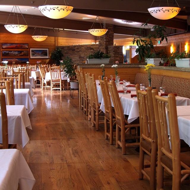 Wooden tables, chairs, and round lights in a restaurant.