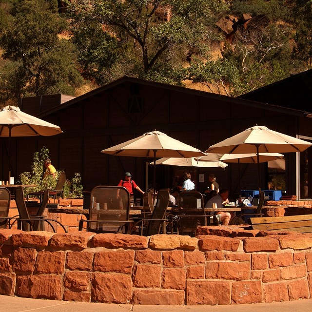 Umbrellas on a patio with tables and a small sandstone brick wall