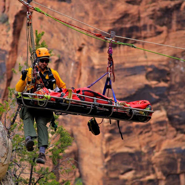 A search and rescue crew lowers a person down the canyon via highline.