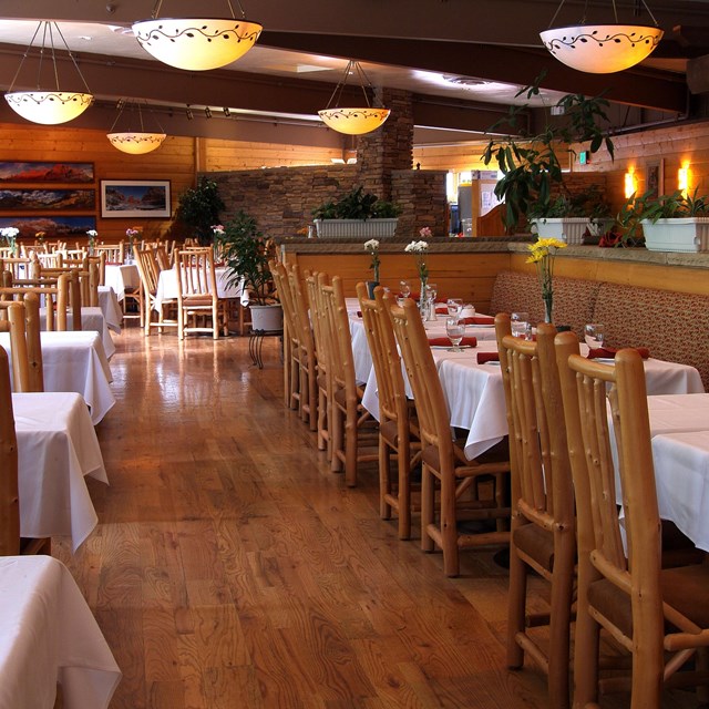Wooden tables and chairs with round lights overhead in a restaurant.