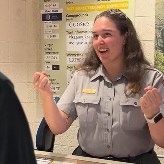 A woman ranger signing to a guest at a desk