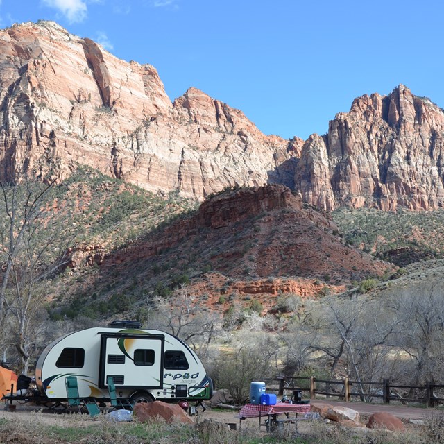 A camper is set up with red mountains in the background.