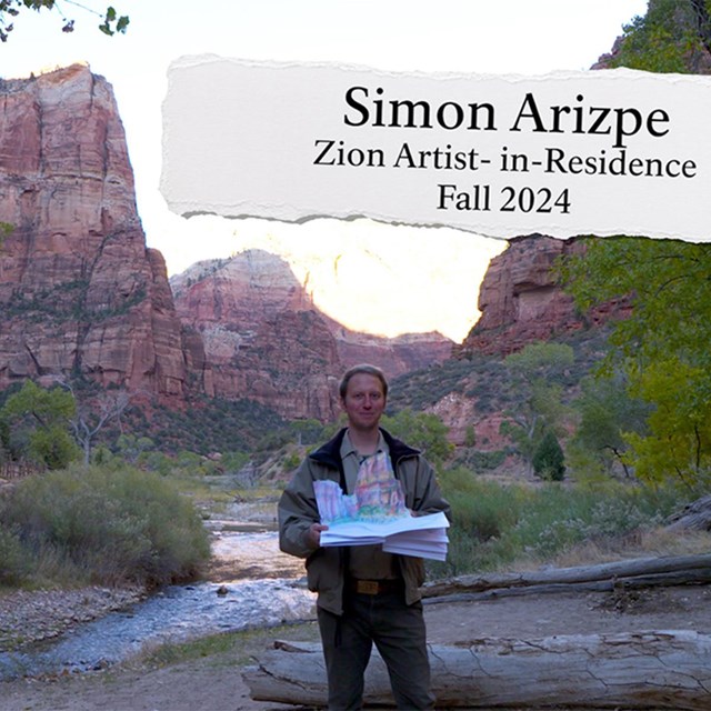 A man holding a pop up book of a sandstone cliff with orange sandstone cliffs in the background