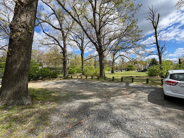 a gravel area for parking cars, with a few trees around
